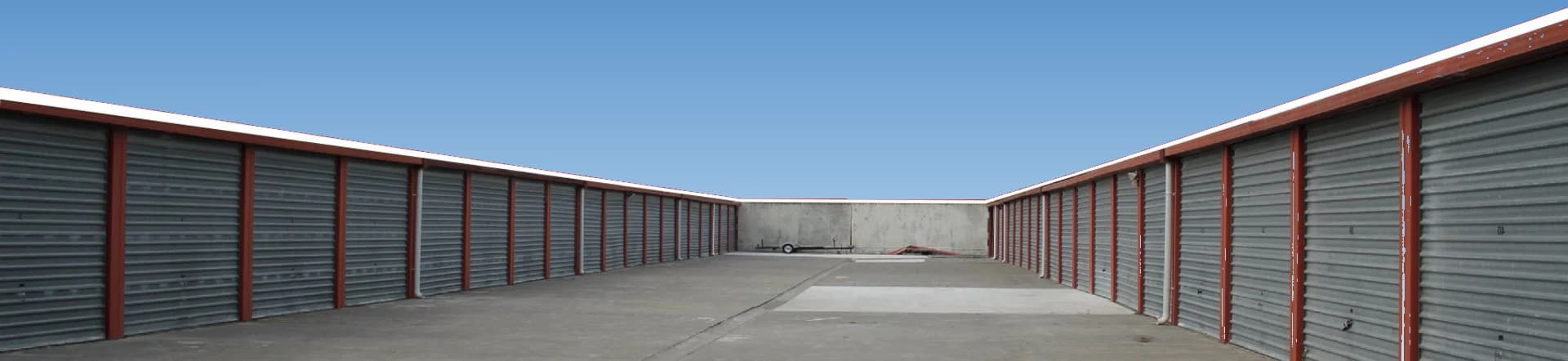 Two long rows of storage unit roller doors facing each other across a wide concrete aisle