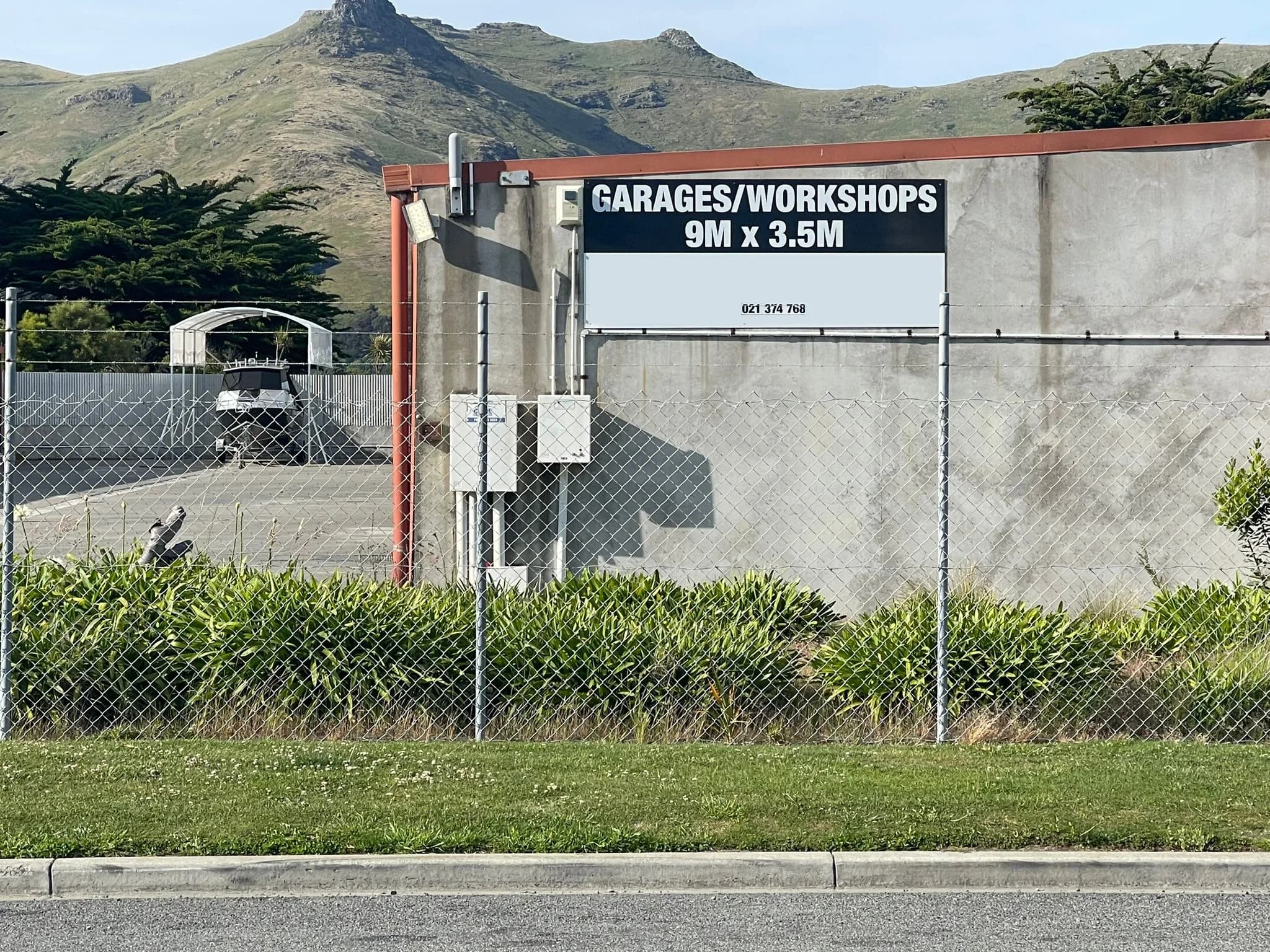 The Ferrymead Storage units behind a security fence, with the Port Hills behind and a Garages and Workshops 9 m by 3.5 m sign